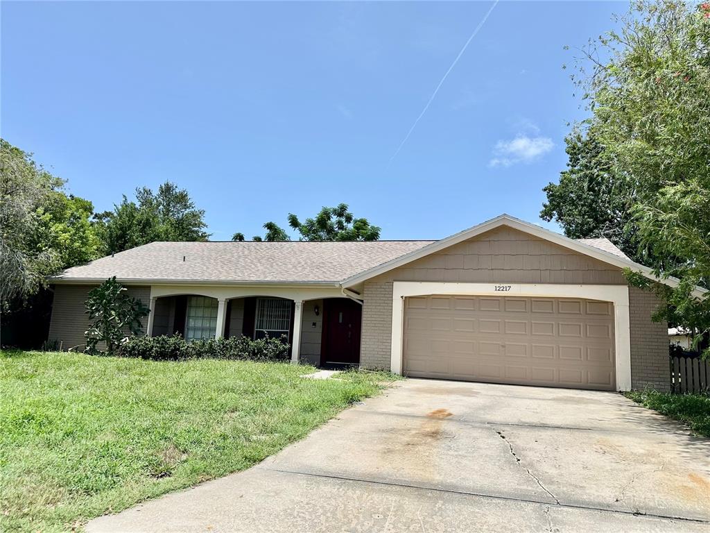 A single-story house with a brick exterior, a two-car garage, and a covered front porch — 12217 BUTTONWOOD ROW, HUDSON, FL