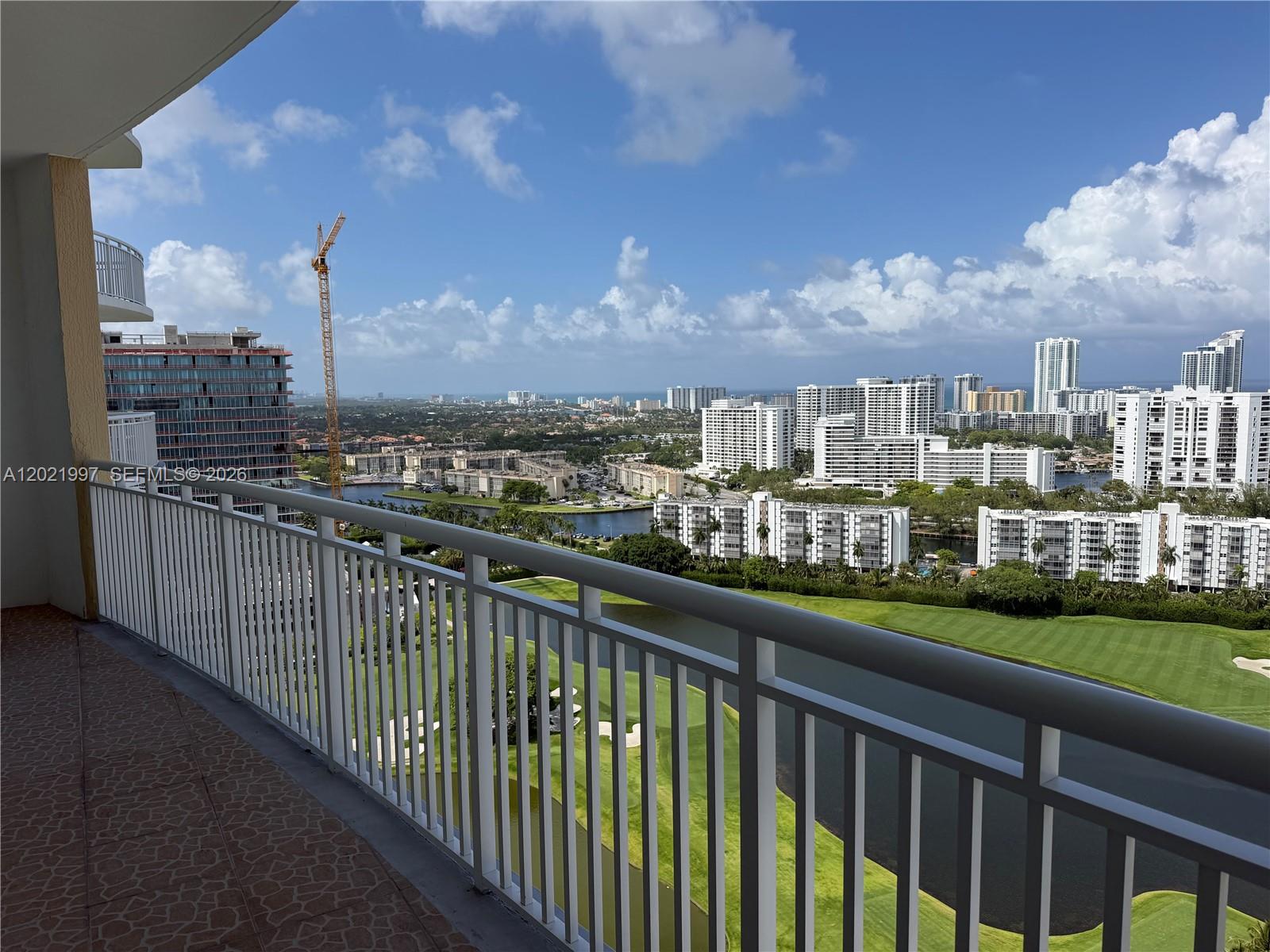 A high-rise balcony overlooks a golf course, a lake, and a cityscape under a blue sky — 1755 E Hallandale Beach Blvd # 2404E, Hallandale Beach FL 33009, HALLANDALE BEACH, FL