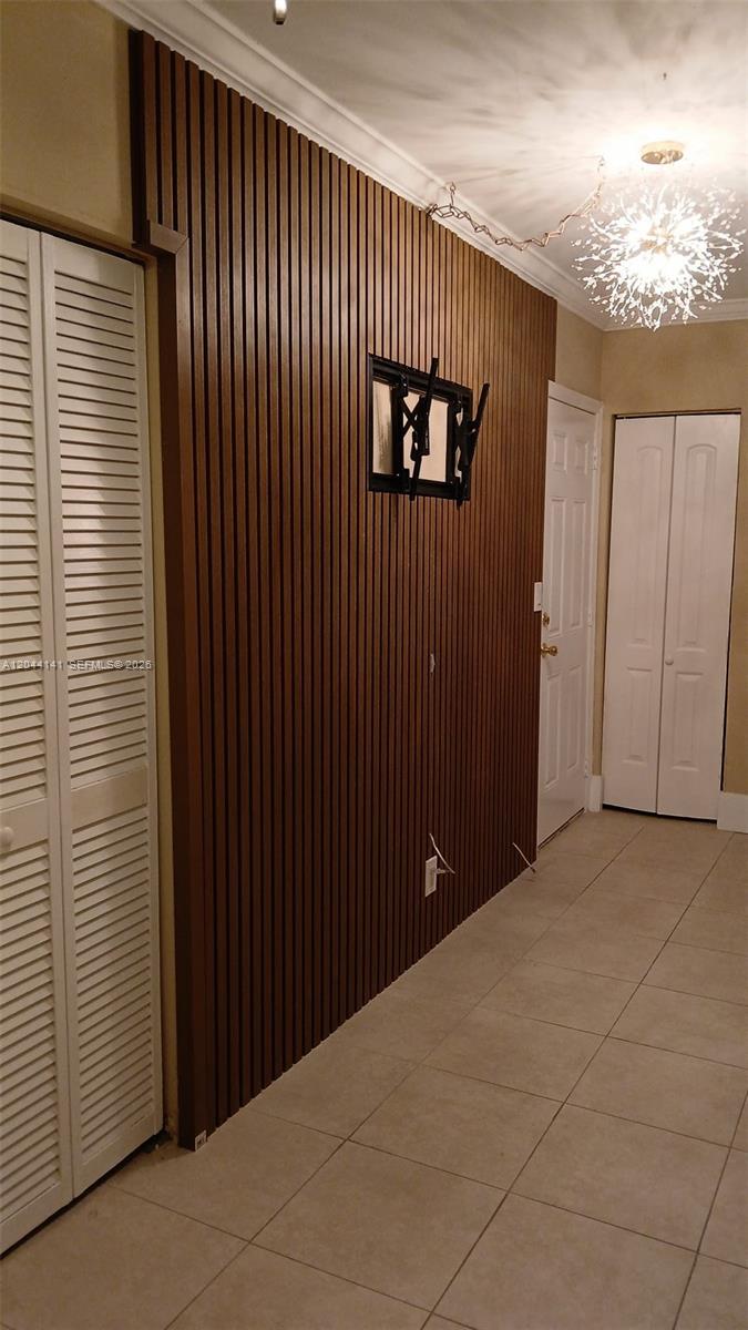 A hallway features a wood-slat accent wall, white louvered closet doors, and a modern chandelier — 10074 E Bay Harbor Dr # 74A, Bay Harbor Islands FL 33154, BAY HARBOR ISLANDS, FL