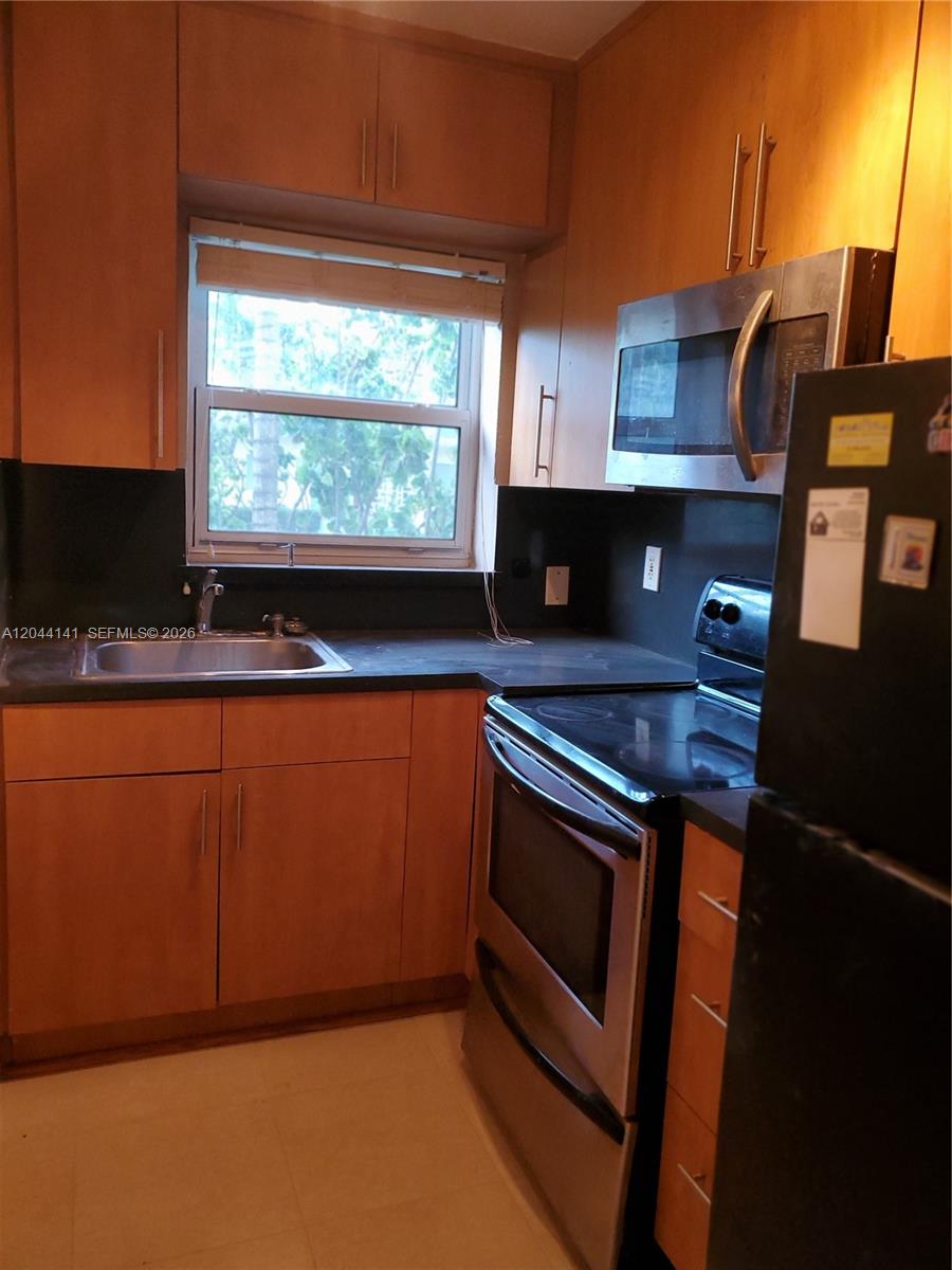 A kitchen features wood cabinets, stainless steel appliances, and a dark countertop with a sink — 10074 E Bay Harbor Dr # 74A, Bay Harbor Islands FL 33154, BAY HARBOR ISLANDS, FL