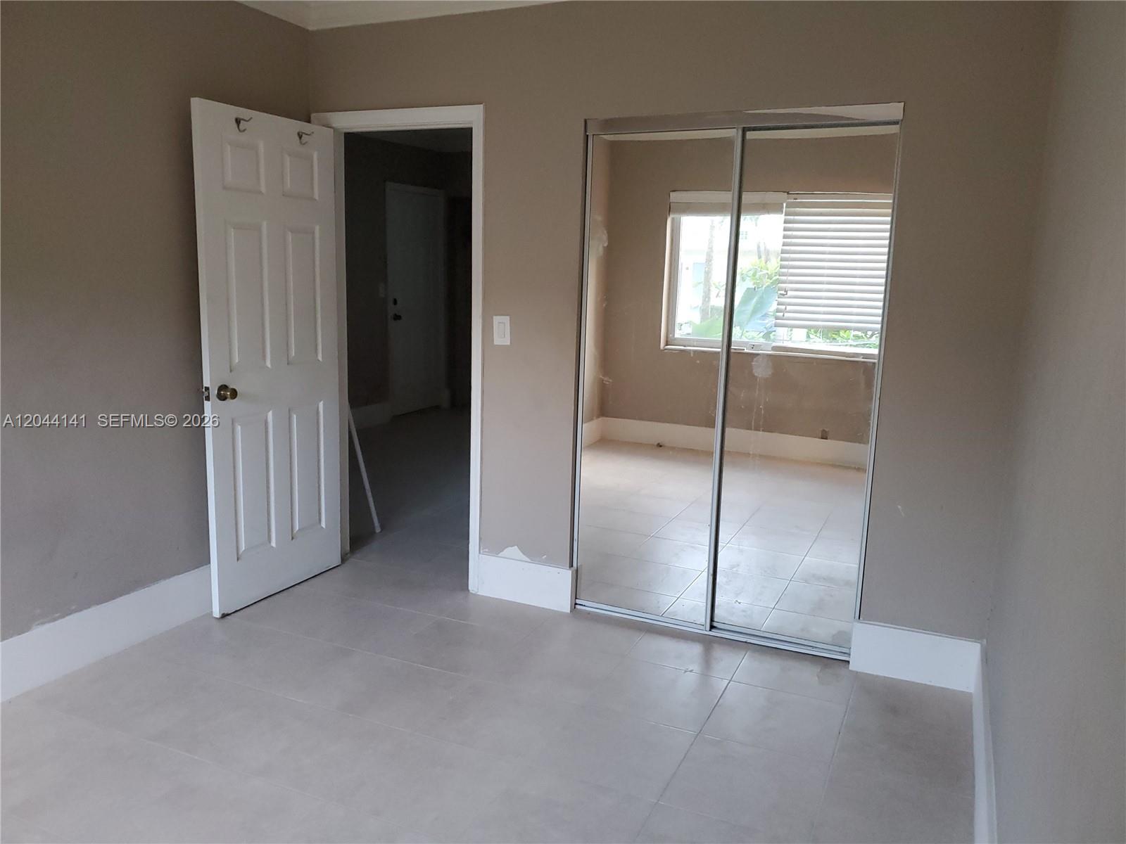 A room with light-colored tile flooring, a white door, and mirrored sliding closet doors — 10074 E Bay Harbor Dr # 74A, Bay Harbor Islands FL 33154, BAY HARBOR ISLANDS, FL
