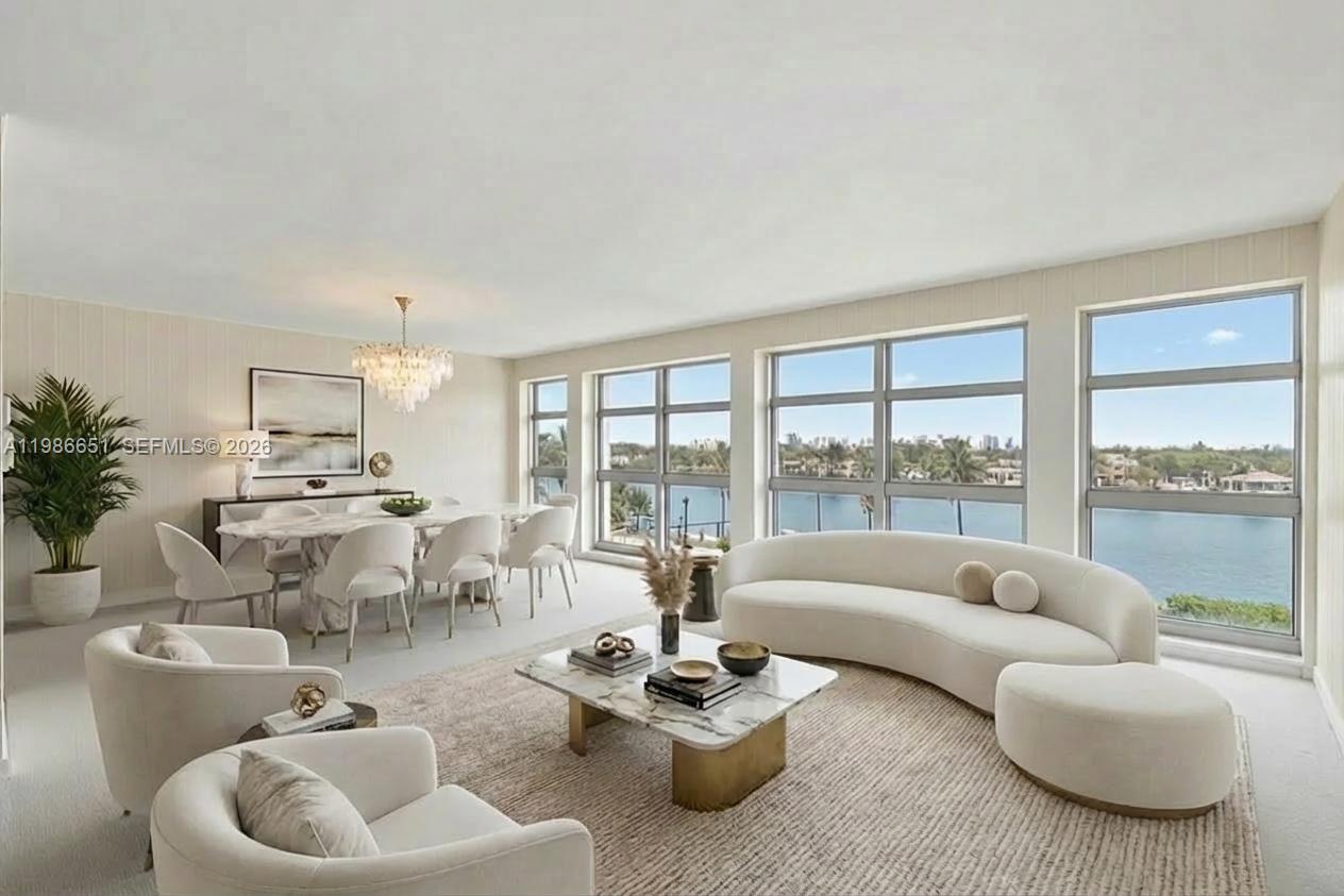 A bright living and dining area features a curved sofa, marble tables, and large windows — 5055 Collins Ave # 5M, Miami Beach FL 33140, MIAMI BEACH, FL