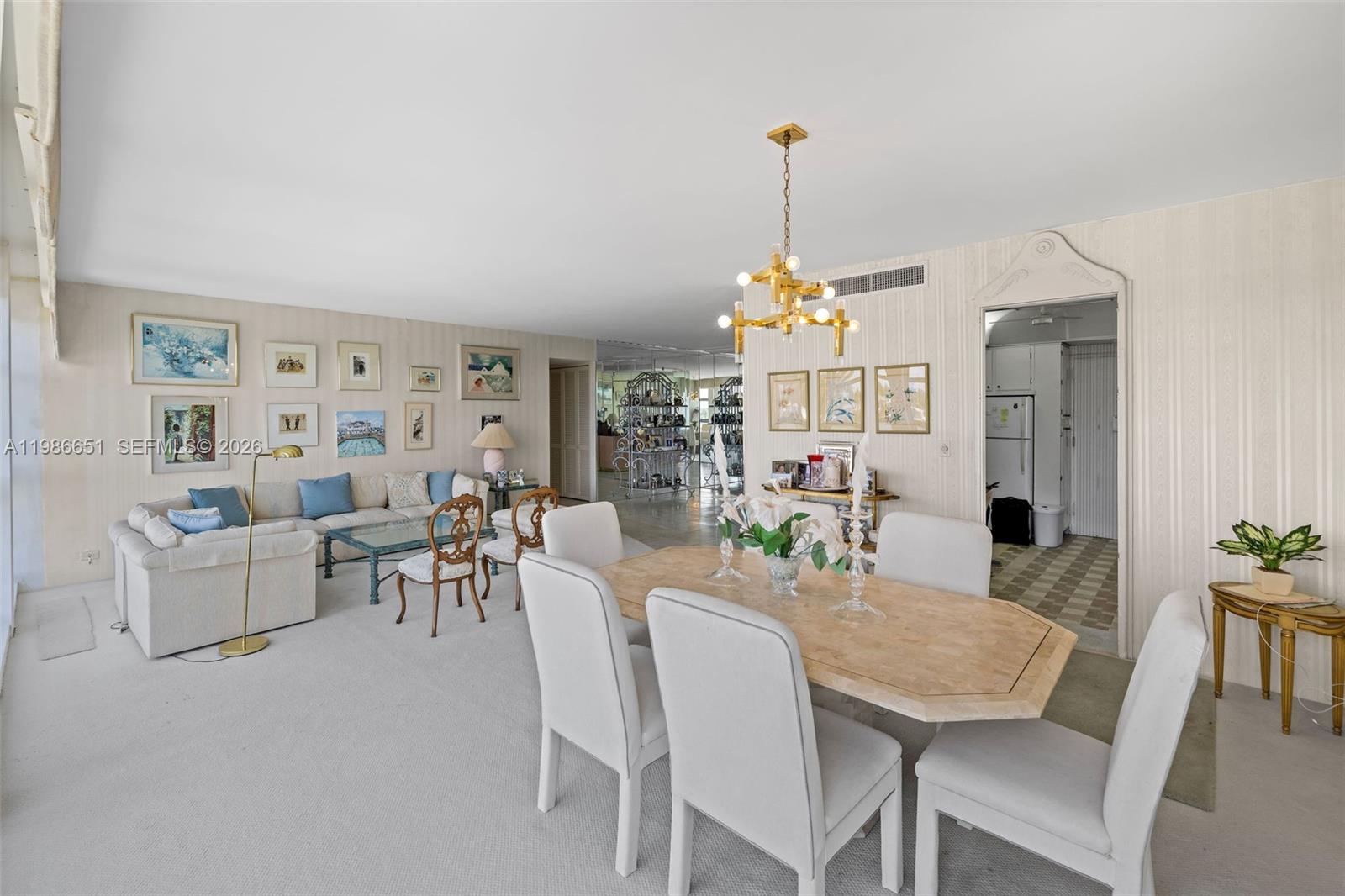 A dining and living area features white carpet, a stone table, and striped wallpaper — 5055 Collins Ave # 5M, Miami Beach FL 33140, MIAMI BEACH, FL