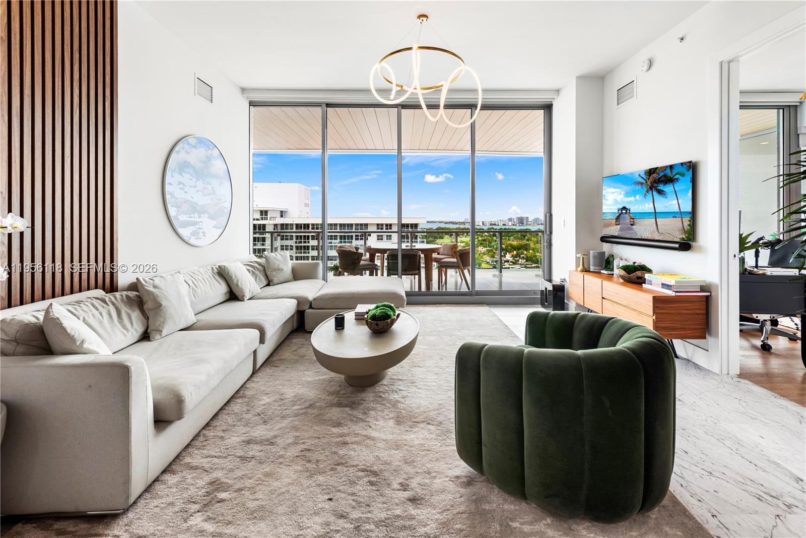 A modern living room features a large sectional sofa, green armchair, and floor-to-ceiling windows — 5775 Collins Ave # 1405, Miami Beach FL 33140, MIAMI BEACH, FL
