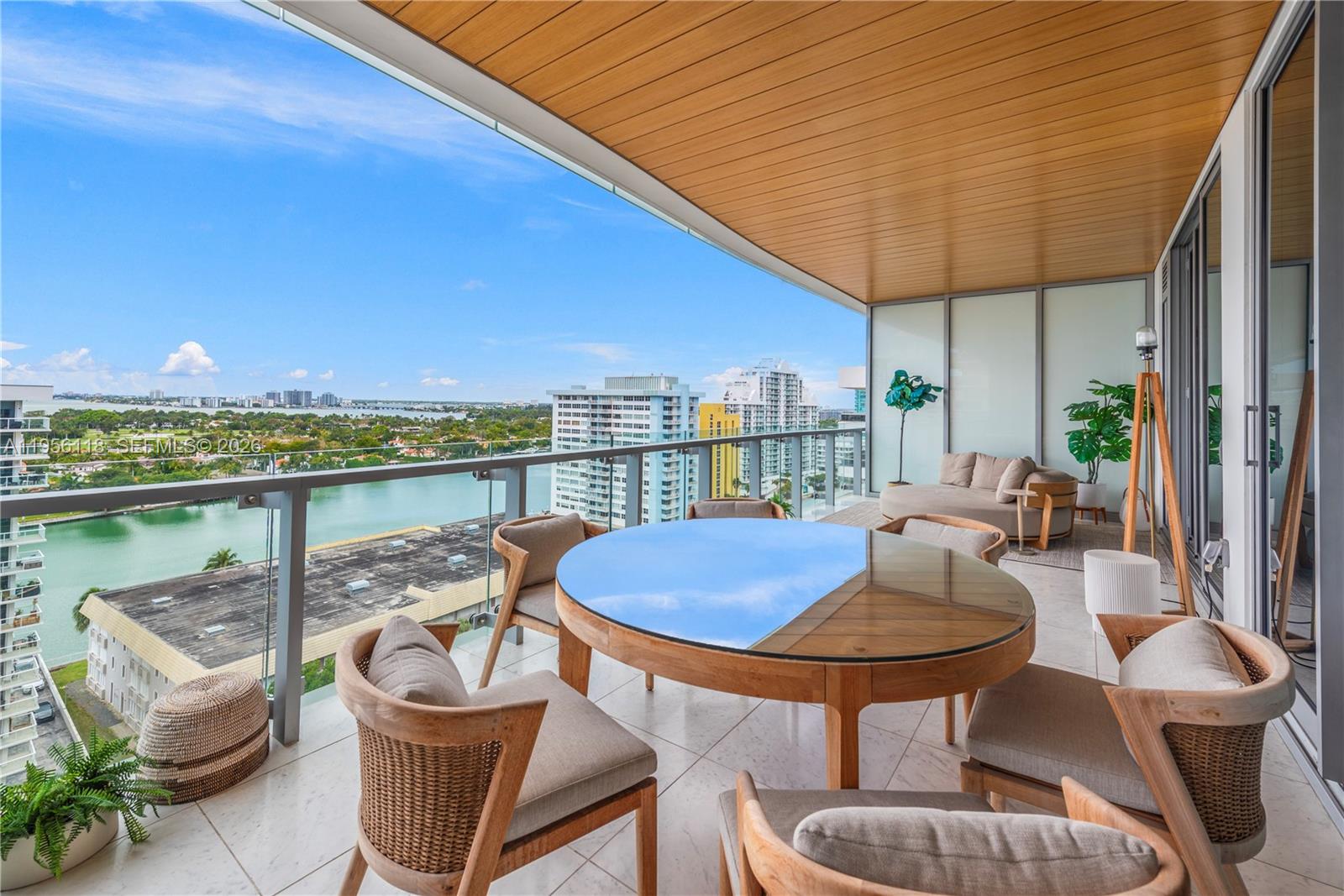 A high-rise balcony features a round dining table, seating, and panoramic waterfront city views — 5775 Collins Ave # 1405, Miami Beach FL 33140, MIAMI BEACH, FL