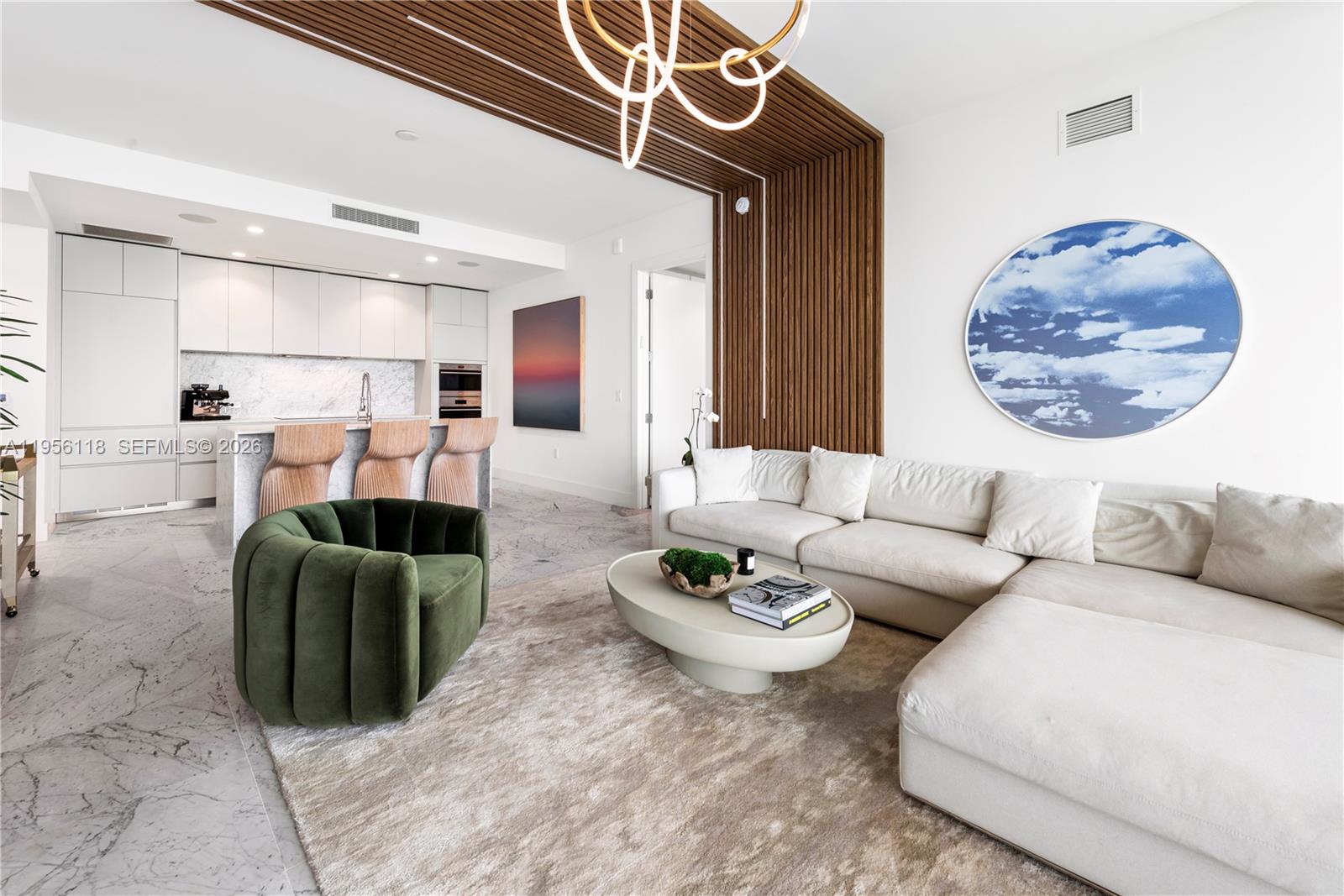 A modern living room features a white sectional sofa, a green velvet chair, and wood-slatted walls — 5775 Collins Ave # 1405, Miami Beach FL 33140, MIAMI BEACH, FL