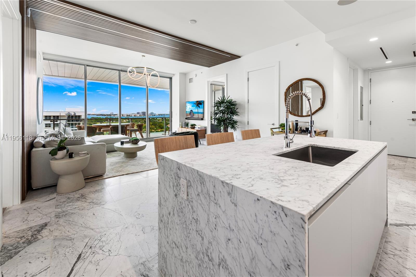 A modern kitchen island with a marble countertop overlooks a living area with floor-to-ceiling windows — 5775 Collins Ave # 1405, Miami Beach FL 33140, MIAMI BEACH, FL