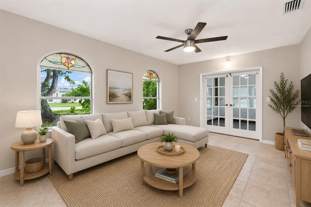 A living room with a sectional sofa, round coffee table, stained-glass windows, and tile floors — 1005 ALSTON LANE, ENGLEWOOD, FL