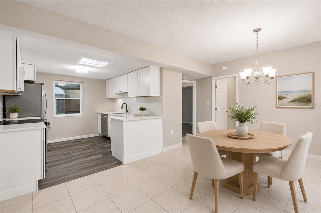 A kitchen and dining area featuring white cabinets, stainless appliances, and a round wooden table — 1005 ALSTON LANE, ENGLEWOOD, FL
