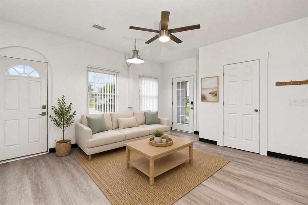 A living room features a beige sofa, a wooden coffee table, and light wood flooring — 1005 ALSTON LANE, ENGLEWOOD, FL