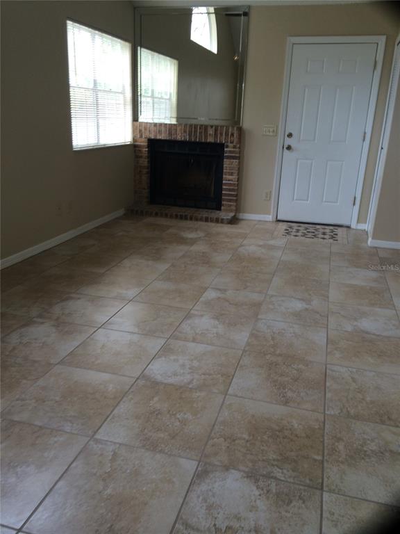 A living room features beige tile flooring, a brick fireplace, and a large wall mirror — 625 GREENCOVE TERRACE UNIT 120, ALTAMONTE SPRINGS, FL
