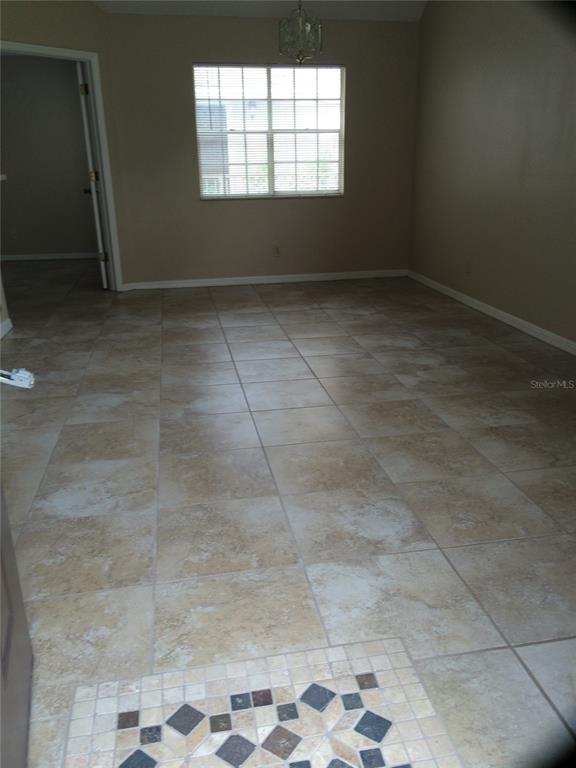 A room with beige tile flooring, a window with blinds, and a decorative tile inlay — 625 GREENCOVE TERRACE UNIT 120, ALTAMONTE SPRINGS, FL