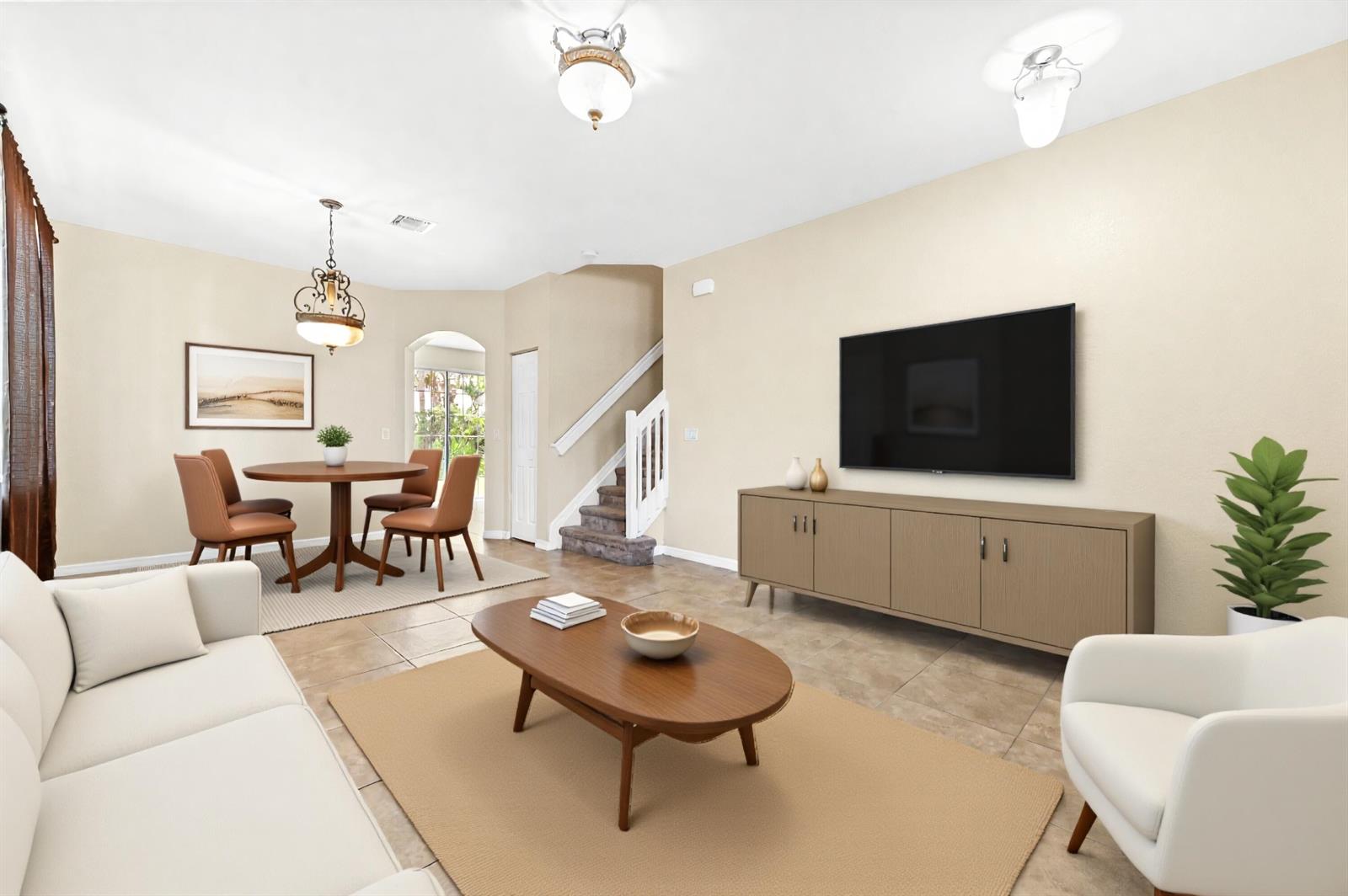 This living and dining area features tile flooring, a mounted television, and a staircase — 6819 Osage Circle, West Palm Beach FL 33413, WEST PALM BEACH, FL