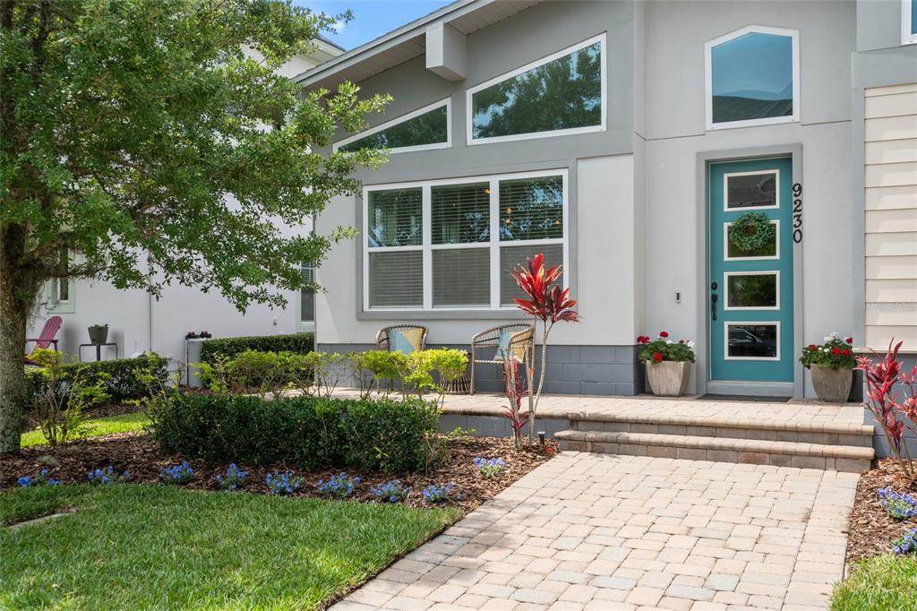 A paved walkway leads to the front entrance of a house with a teal door — 9230 YONATH STREET, ORLANDO, FL