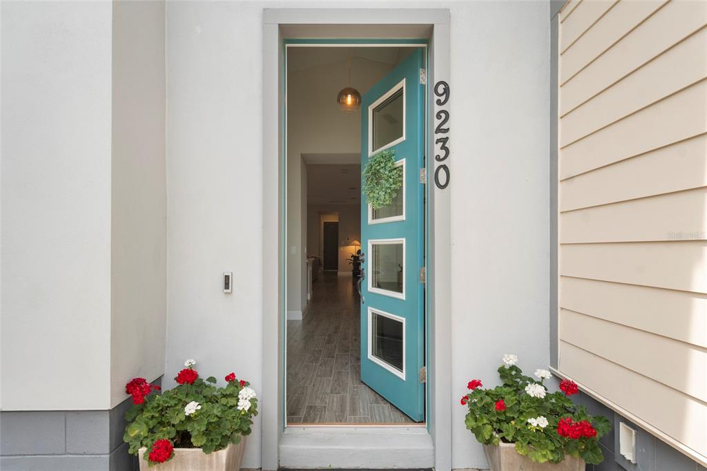 A teal front door with glass panels and house numbers stands open to a home interior — 9230 YONATH STREET, ORLANDO, FL