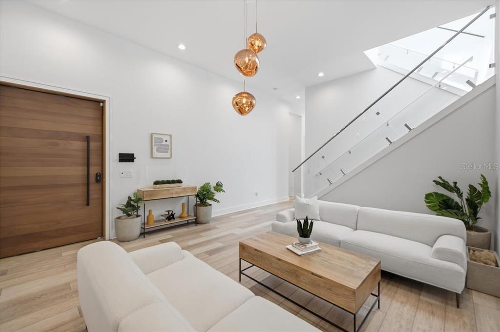 A modern living room features white sofas, a wooden coffee table, and a glass-railed staircase — 2701 N POPLAR AVENUE, TAMPA, FL