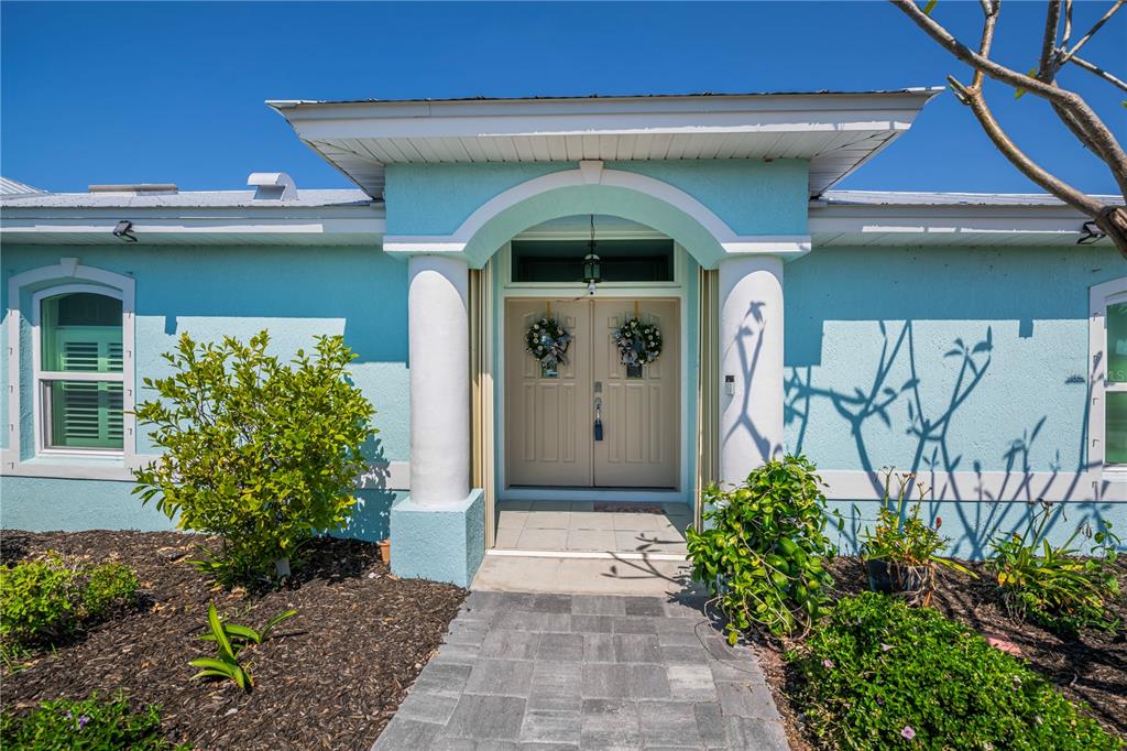 The exterior of a light blue house features a covered entryway with two white columns — 409 BOUNDARY BOULEVARD, ROTONDA WEST, FL