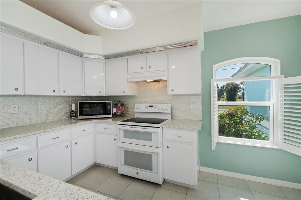 A living room with light blue walls, wood-look tile flooring, and a large oak entertainment center — 409 BOUNDARY BOULEVARD, ROTONDA WEST, FL