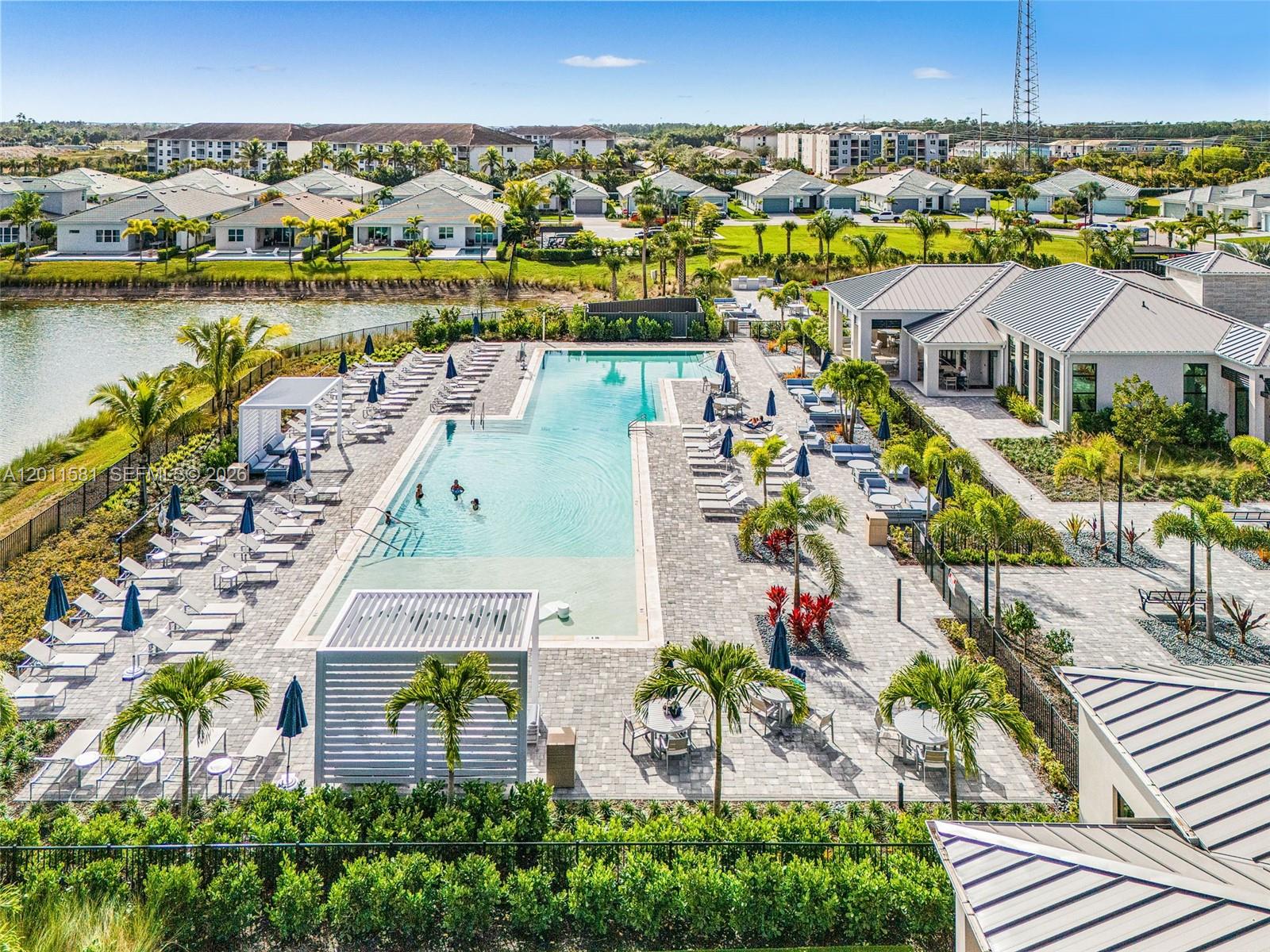 An aerial view shows a rectangular swimming pool surrounded by lounge chairs and palm trees — 9087 Kite Ln, Naples FL 34114, NAPLES, FL