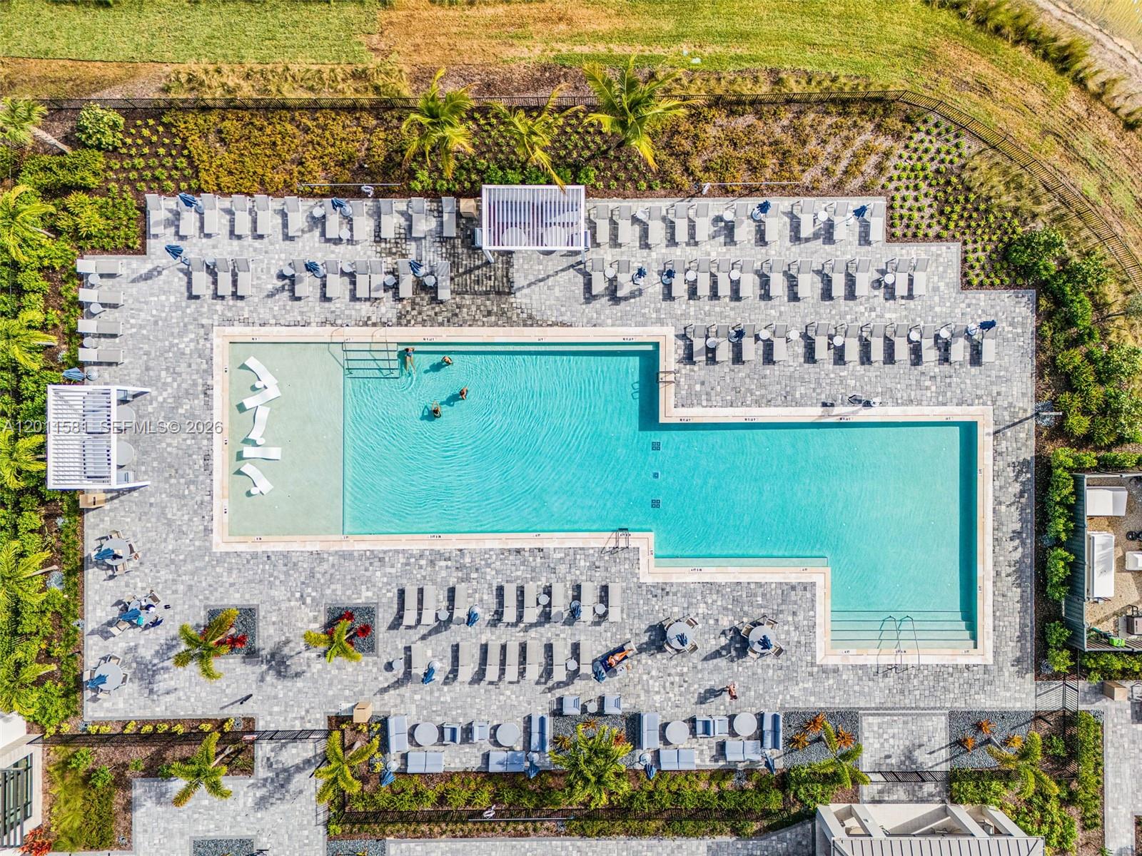 An aerial view shows a rectangular swimming pool with lounge chairs on a paved deck — 9087 Kite Ln, Naples FL 34114, NAPLES, FL