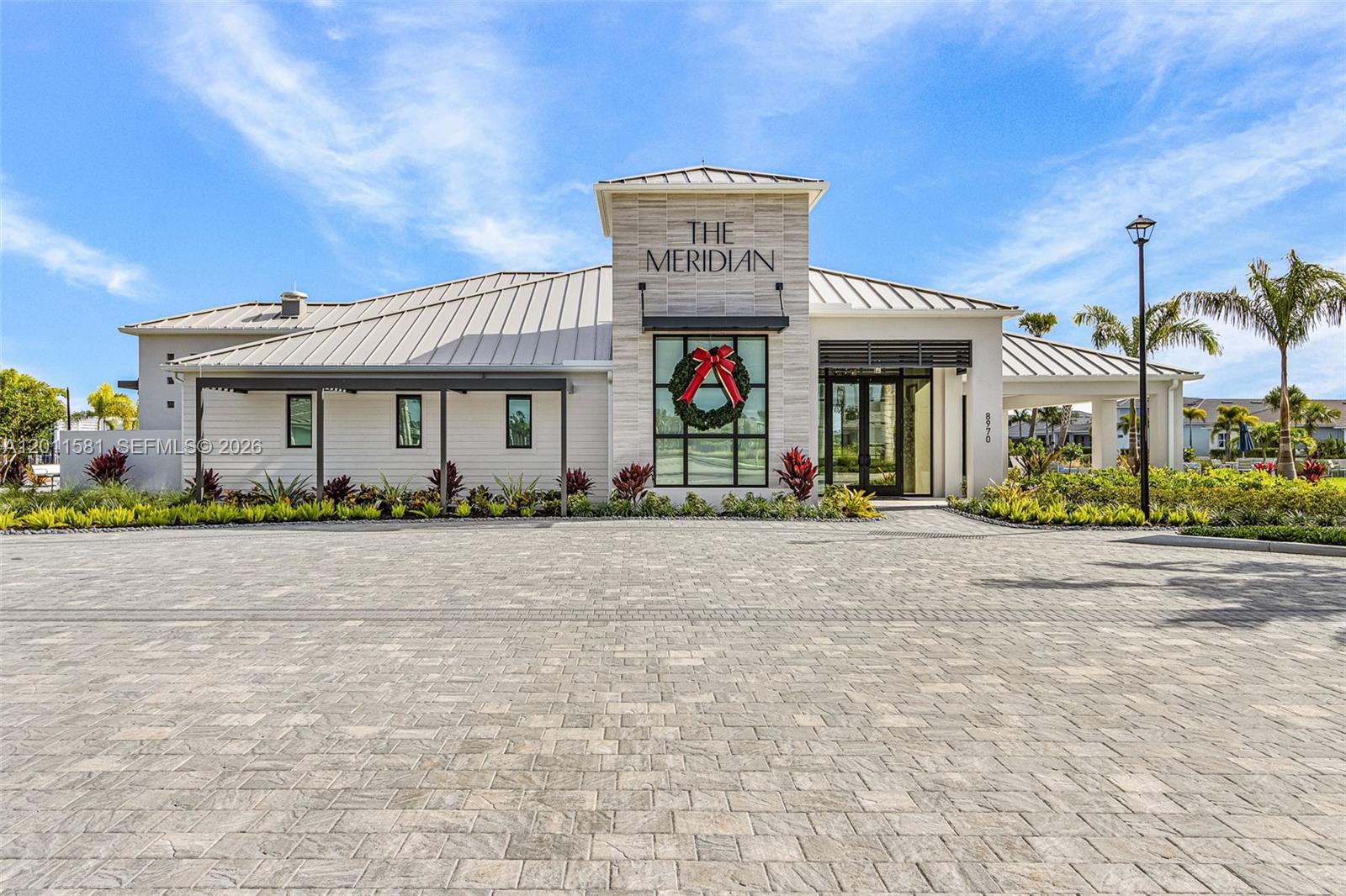 A modern, single-story building with a stone facade, metal roof, and a large Christmas wreath — 9087 Kite Ln, Naples FL 34114, NAPLES, FL