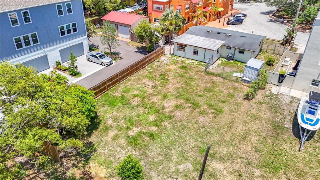An aerial view shows a vacant grassy lot bordered by a wooden fence and buildings — 2304 N HIGHLAND AVENUE, TAMPA, FL