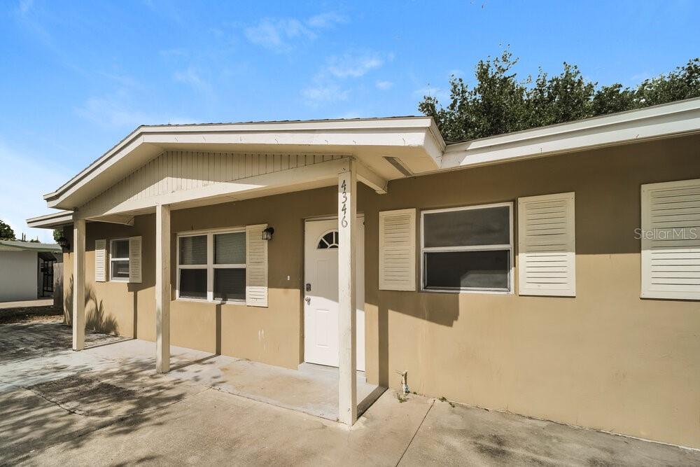 A tan, single-story house exterior features a covered entryway, white shutters, and a concrete driveway — 4346 TUFTS AVENUE, FORT MYERS, FL