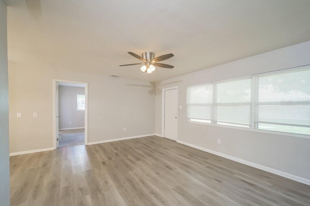 An empty living room features light gray walls, wood-look flooring, a ceiling fan, and windows — 4346 TUFTS AVENUE, FORT MYERS, FL