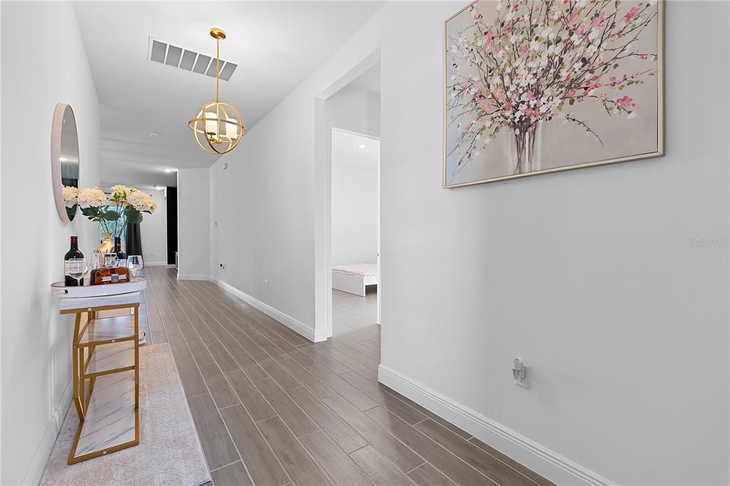 A hallway with light wood-look tile flooring, a gold pendant light, and a console table — 14422 CREST PALM AVENUE, WINDERMERE, FL