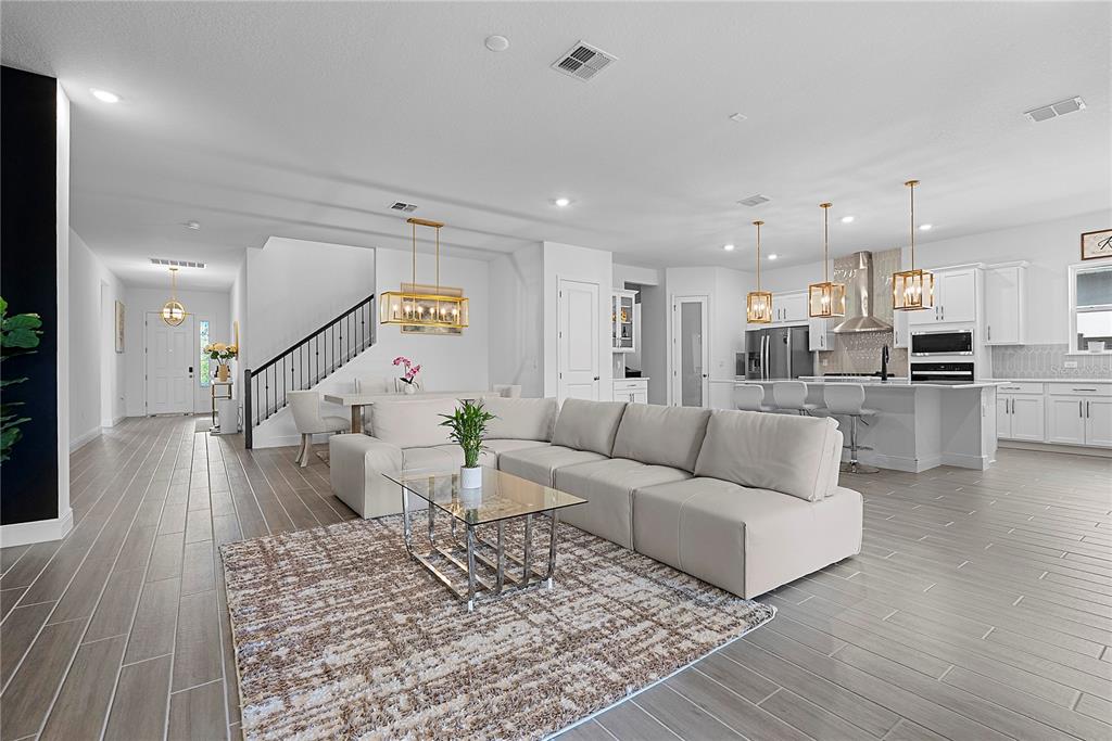 An open-concept living room and kitchen feature white cabinetry, tile flooring, and a sectional sofa — 14422 CREST PALM AVENUE, WINDERMERE, FL