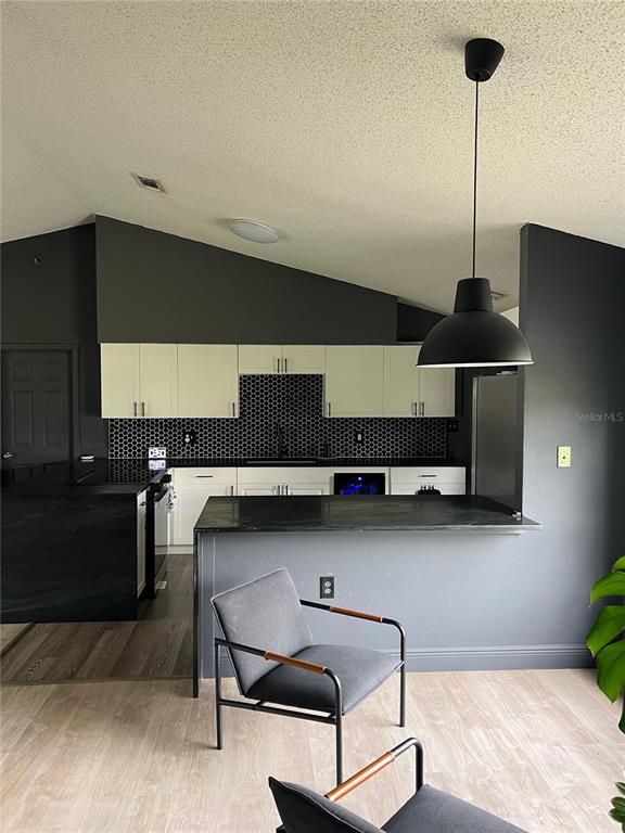 A kitchen features white cabinets, a black honeycomb backsplash, and a dark countertop peninsula — 906 SAN PAULO WAY, KISSIMMEE, FL