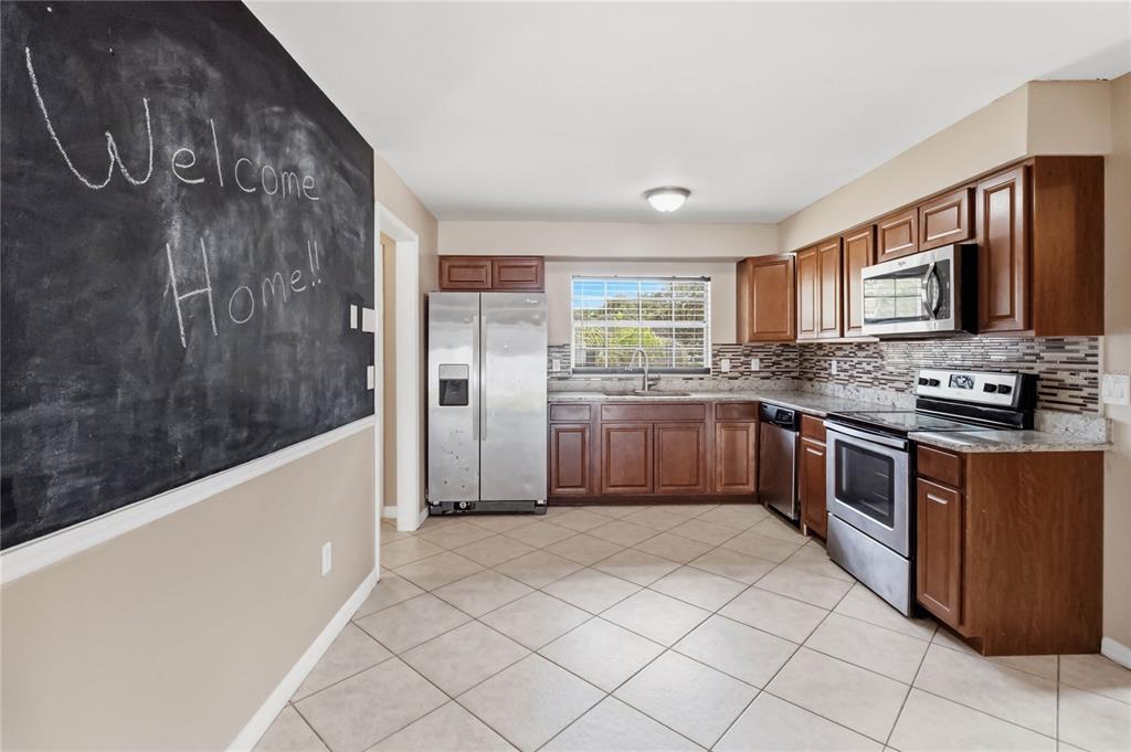 A kitchen features dark wood cabinets, stainless steel appliances, tile flooring, and a chalkboard wall — 825 TURTLE MOUND DRIVE, CASSELBERRY, FL