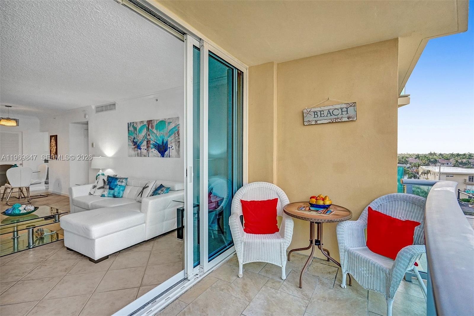 A balcony with wicker chairs and a small table overlooks a view of buildings — 2501 S Ocean Dr, Hollywood FL 33019, HOLLYWOOD, FL