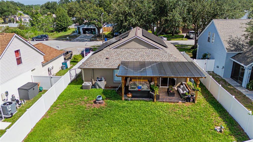 An aerial view of a backyard featuring a covered patio, hot tub, and white fencing — 24328 MISTWOOD COURT, LUTZ, FL