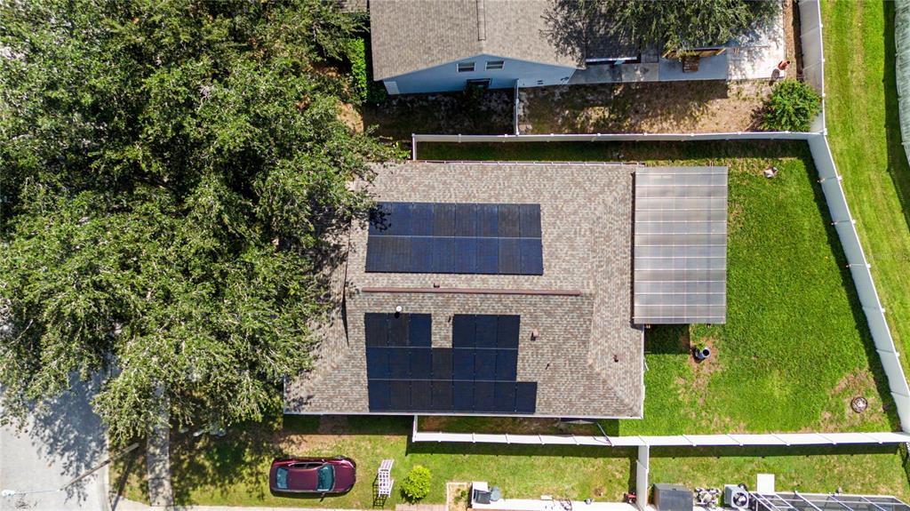 An aerial view shows a house roof with solar panels and a covered patio area — 24328 MISTWOOD COURT, LUTZ, FL