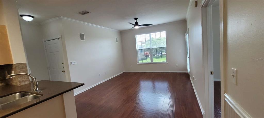 A living room with dark wood flooring, a ceiling fan, and an adjacent kitchen counter — 14328 FREDRICKSBURG DRIVE UNIT 601, ORLANDO, FL