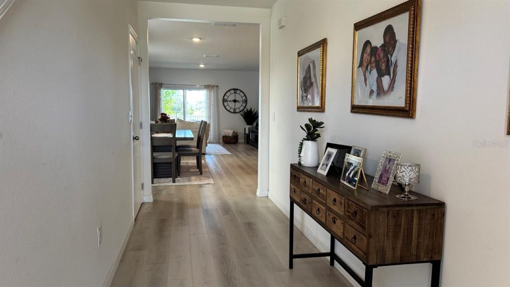 A hallway with light wood flooring leads to a dining area and living space — 1724 POST OAK DRIVE, DAVENPORT, FL