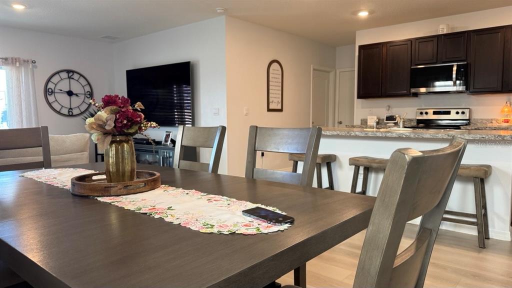 A dining area with a wooden table and chairs opens into a kitchen with dark cabinets — 1724 POST OAK DRIVE, DAVENPORT, FL