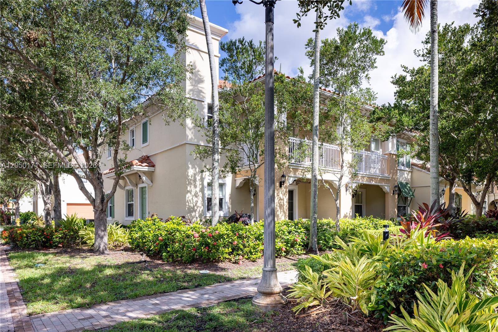 A two-story beige townhouse features a balcony, a chimney, and lush landscaping — 3300 NW 126th Ter, Sunrise FL 33323, SUNRISE, FL