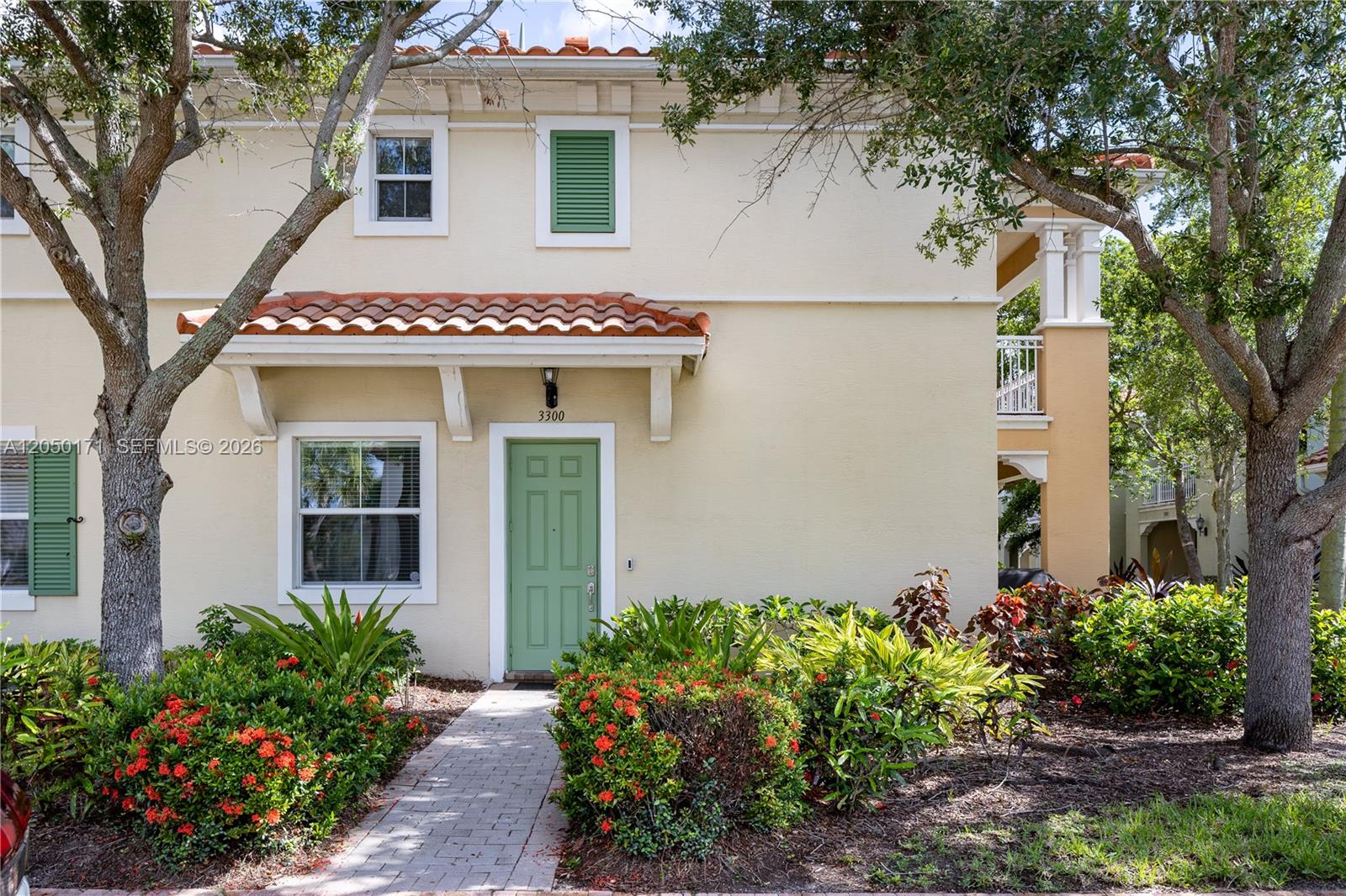 A two-story stucco building features a green front door, a tiled roof, and landscaped gardens — 3300 NW 126th Ter, Sunrise FL 33323, SUNRISE, FL
