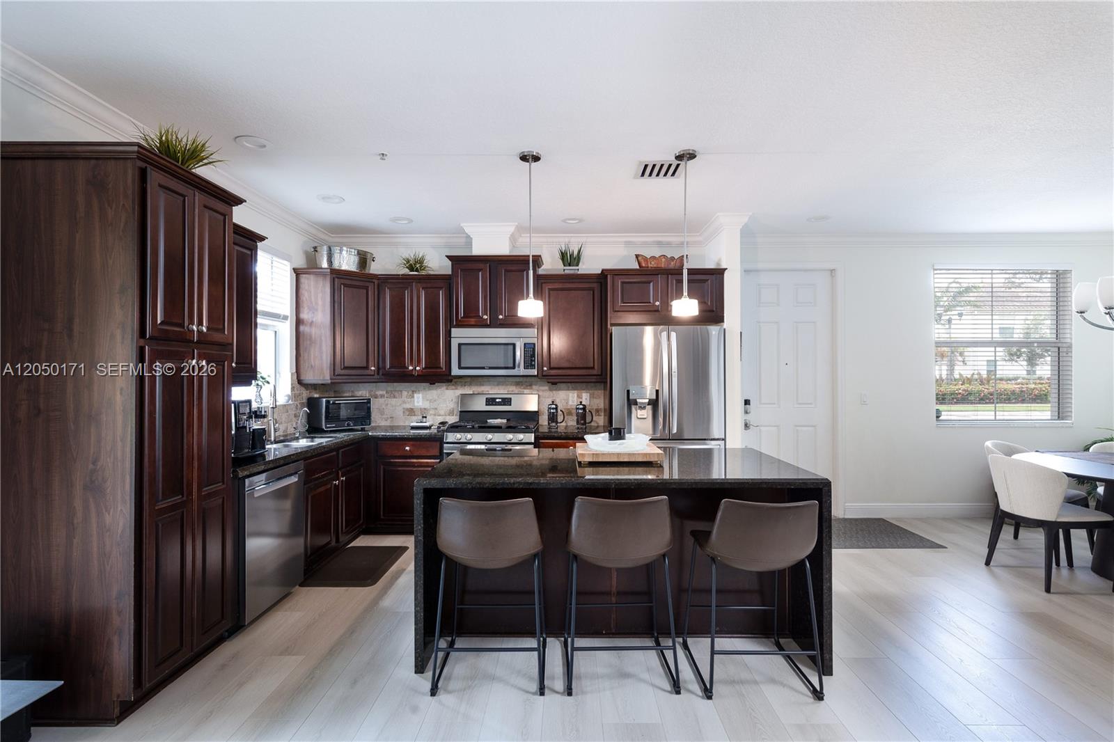A kitchen features dark wood cabinets, granite countertops, a central island, and stainless steel appliances — 3300 NW 126th Ter, Sunrise FL 33323, SUNRISE, FL