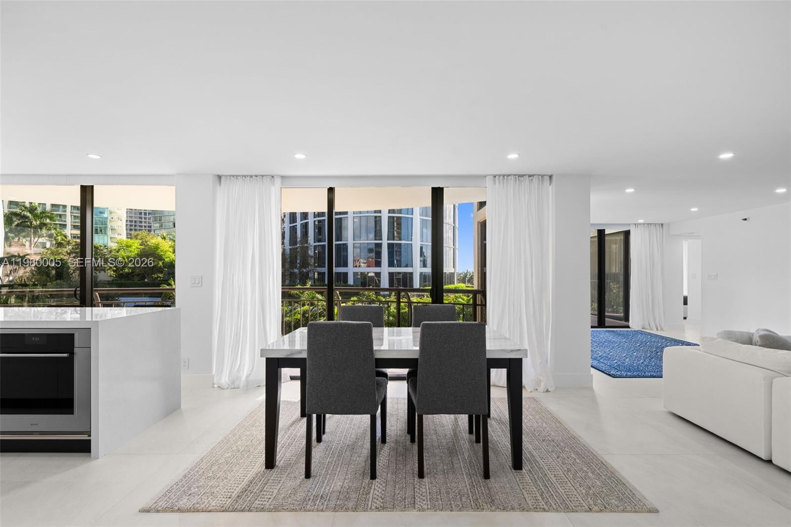A dining area with a marble-topped table and four gray chairs sits before floor-to-ceiling windows — 2843 S Bayshore Dr # 5F, Miami FL 33133, MIAMI, FL