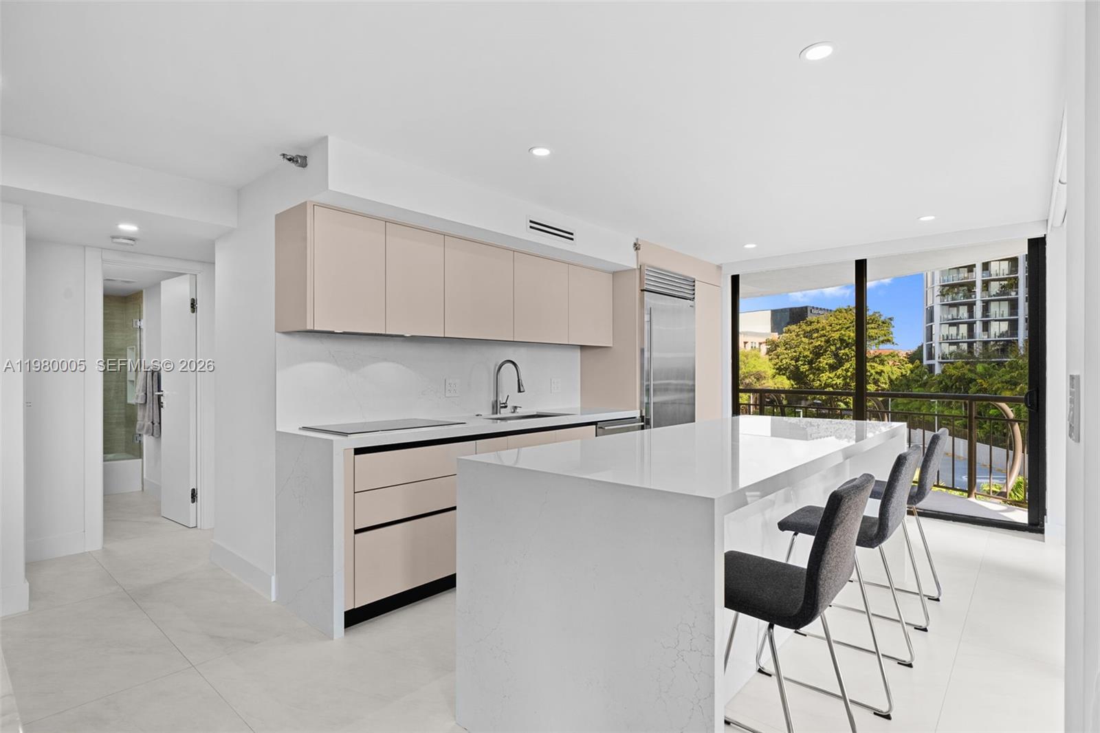 A modern kitchen features light-toned cabinetry, a white quartz island, and a balcony view — 2843 S Bayshore Dr # 5F, Miami FL 33133, MIAMI, FL