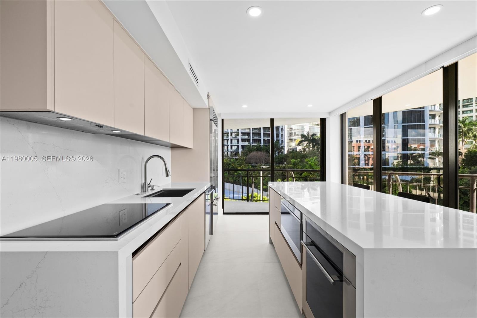 A modern kitchen features light-toned cabinetry, white quartz countertops, and floor-to-ceiling windows overlooking trees — 2843 S Bayshore Dr # 5F, Miami FL 33133, MIAMI, FL