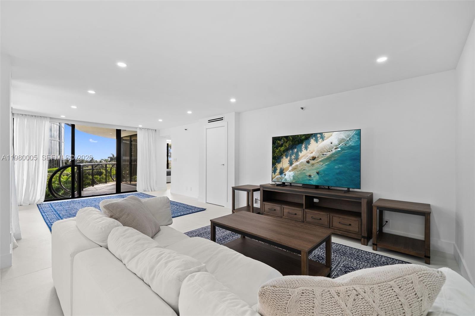 A living room features a white sofa, a wooden media console, and a balcony view — 2843 S Bayshore Dr # 5F, Miami FL 33133, MIAMI, FL