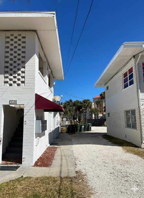 Two white multi-story buildings flank a gravel driveway leading to a row of trash bins — 938 N GRANDVIEW AVENUE, DAYTONA BEACH, FL