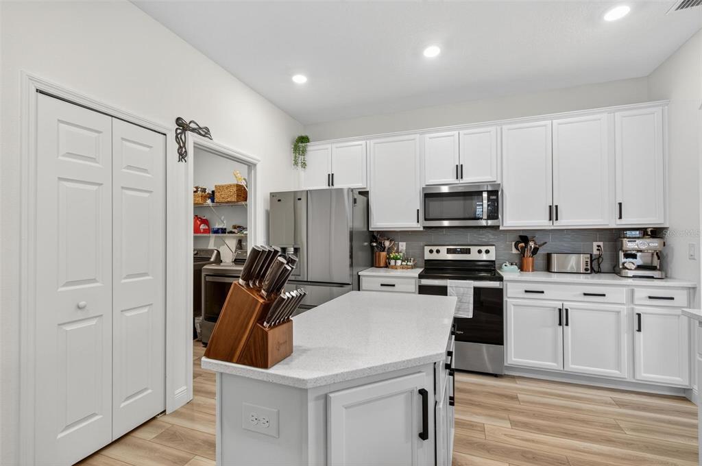 A kitchen with white cabinets, stainless steel appliances, a center island, and wood-look flooring — 2 RIDGE ROAD, PALM COAST, FL