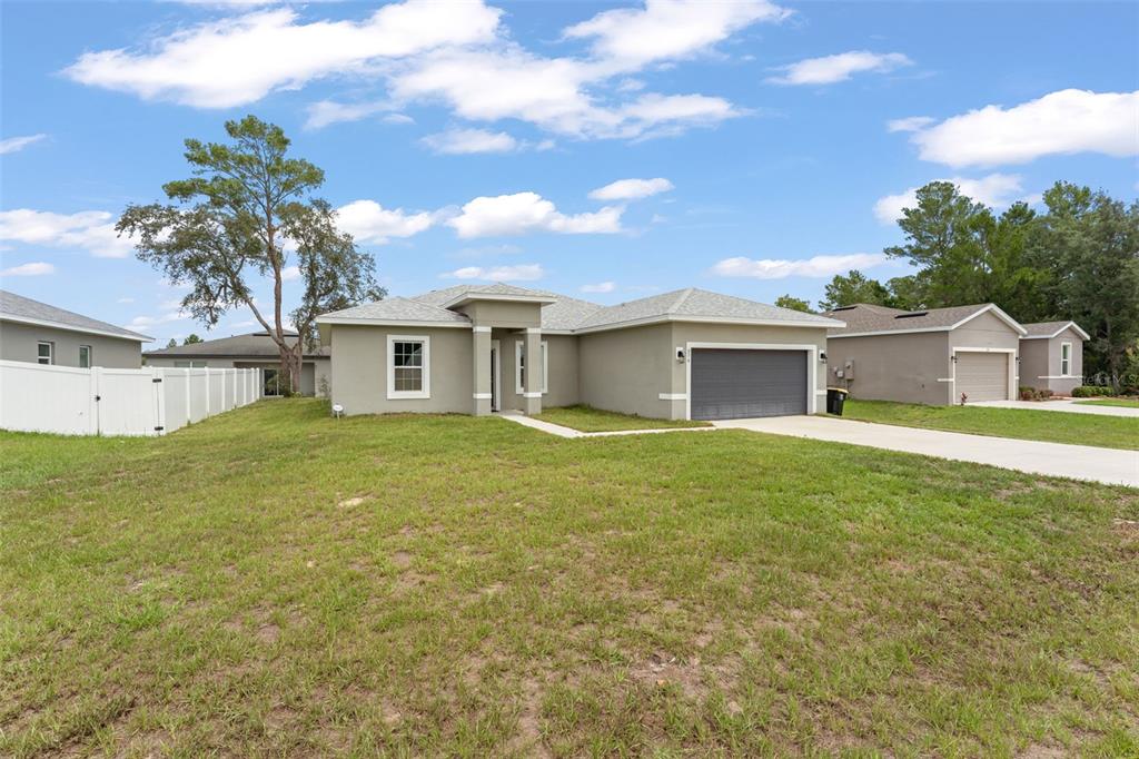 A single-story house with a gray exterior, a two-car garage, and a large front lawn — 274 ELM COURT, KISSIMMEE, FL