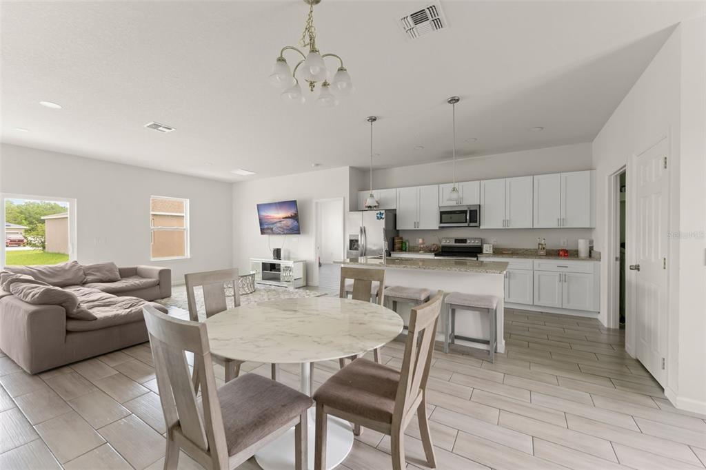 An open-concept kitchen and living area features white cabinets, granite countertops, and tile flooring — 274 ELM COURT, KISSIMMEE, FL
