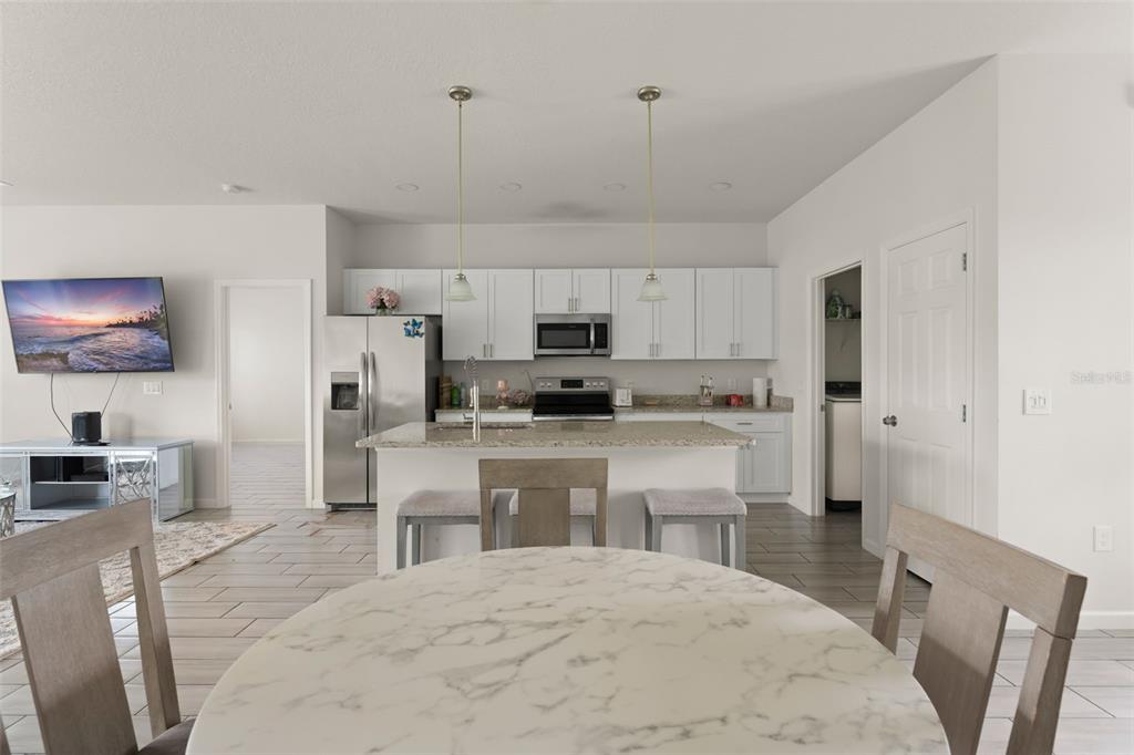 A kitchen with white cabinets, granite countertops, and an island with bar seating — 274 ELM COURT, KISSIMMEE, FL